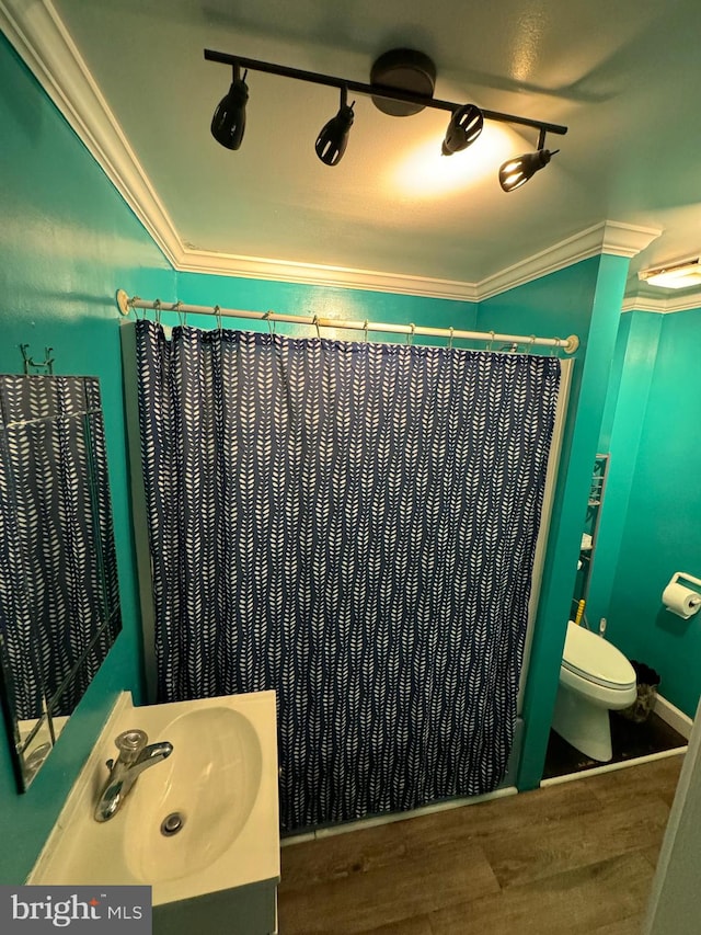 bathroom with crown molding, sink, wood-type flooring, and toilet