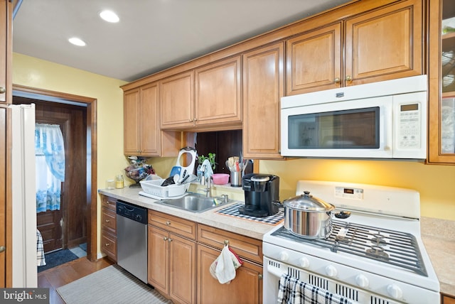 kitchen with hardwood / wood-style flooring, white appliances, and sink