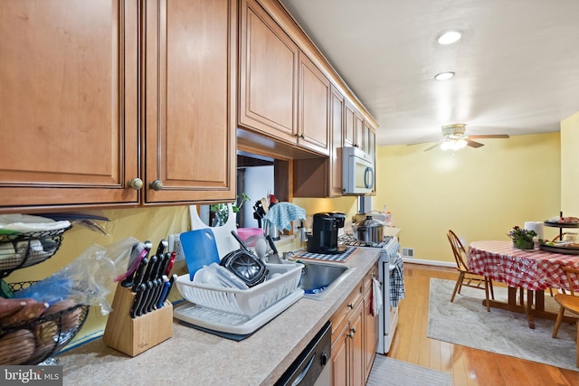 kitchen with ceiling fan, sink, stainless steel appliances, and light hardwood / wood-style floors