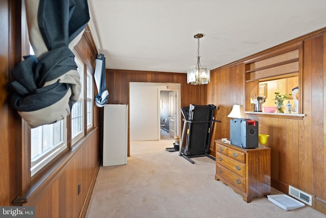 interior space featuring light carpet, wooden walls, crown molding, an inviting chandelier, and hanging light fixtures