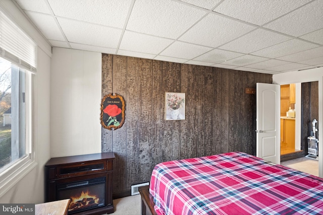 bedroom with wooden walls and a drop ceiling