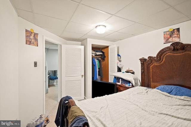 bedroom with carpet, a paneled ceiling, and a closet