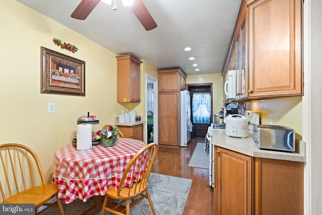 kitchen featuring ceiling fan, white appliances, and dark wood-type flooring