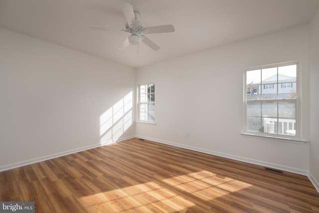 unfurnished room featuring hardwood / wood-style floors, ceiling fan, and a wealth of natural light