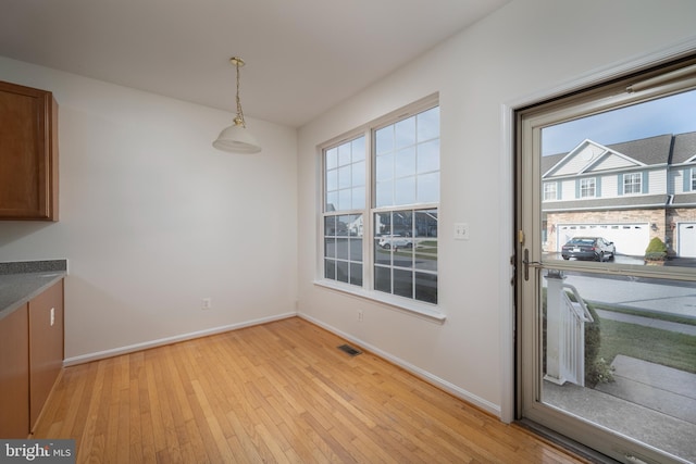 unfurnished dining area featuring light wood-type flooring and a wealth of natural light