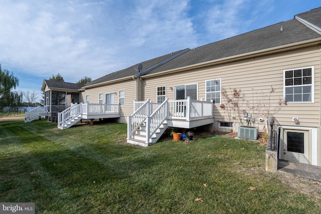 back of property with a wooden deck, a yard, and central AC unit