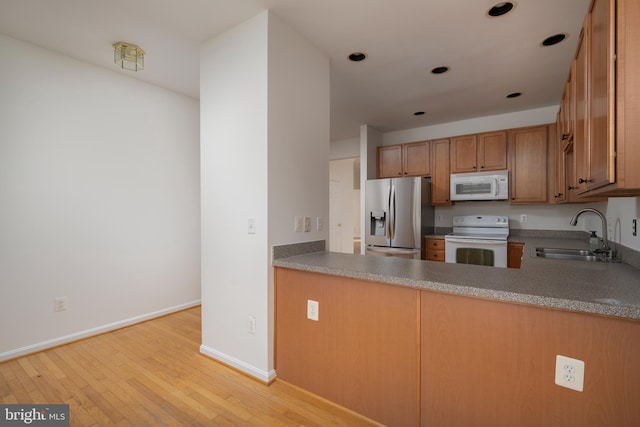 kitchen featuring sink, white appliances, and light hardwood / wood-style flooring