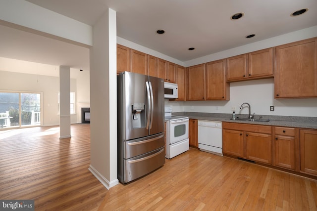 kitchen with light wood-type flooring, white appliances, and sink