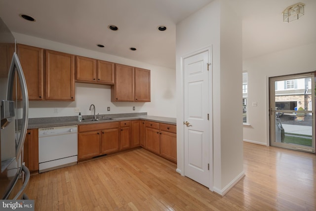 kitchen featuring white dishwasher, stainless steel fridge, sink, and light hardwood / wood-style flooring