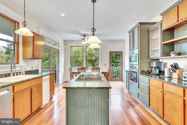 kitchen featuring pendant lighting, a center island, sink, light wood-type flooring, and appliances with stainless steel finishes