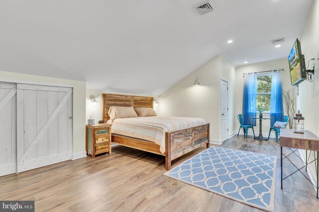 bedroom with light wood-type flooring and a barn door