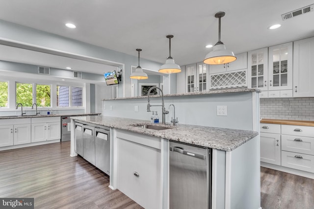 kitchen featuring an island with sink, white cabinetry, hanging light fixtures, and sink