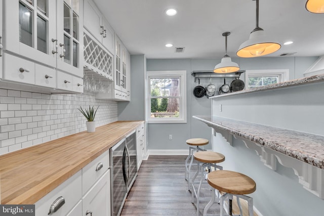 kitchen with hanging light fixtures, tasteful backsplash, dark hardwood / wood-style flooring, butcher block countertops, and white cabinets