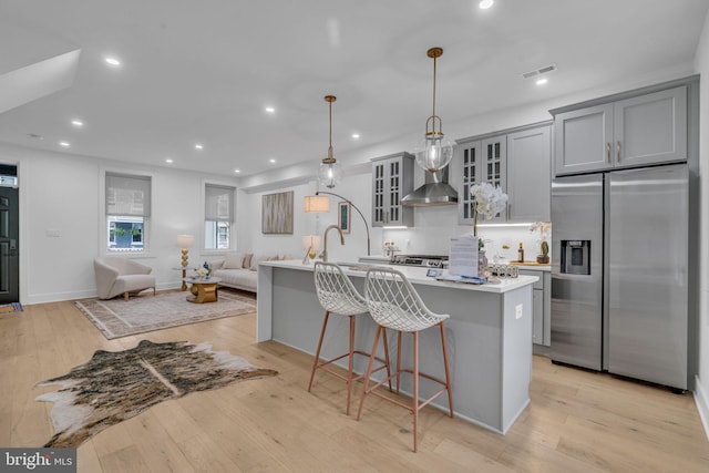 kitchen featuring stainless steel fridge, light wood-type flooring, decorative light fixtures, and gray cabinets