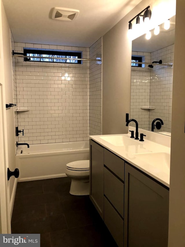 full bathroom featuring tile patterned flooring, vanity, toilet, and tiled shower / bath combo