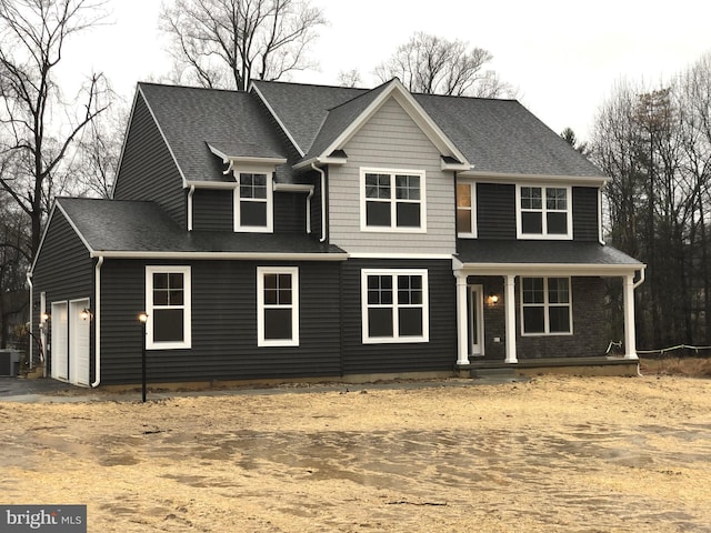 view of front facade with covered porch, central AC, and a garage