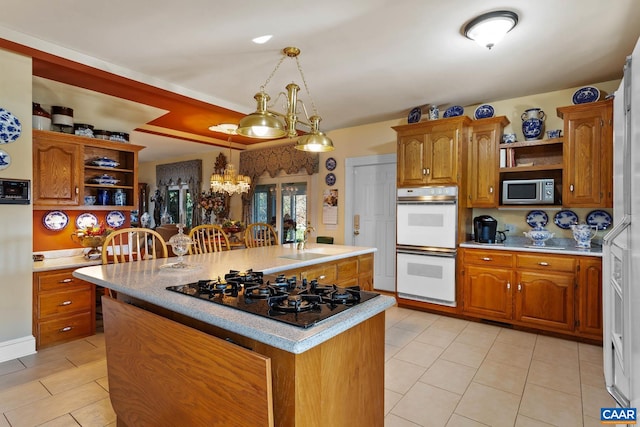 kitchen featuring black gas stovetop, white double oven, sink, pendant lighting, and a center island