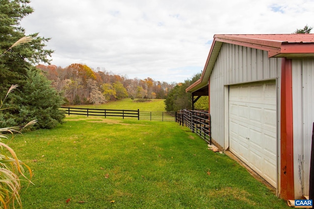 view of yard featuring a rural view, an outdoor structure, and a garage