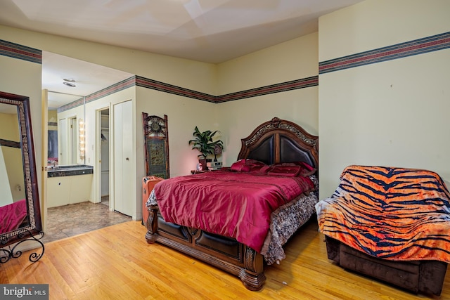 bedroom with connected bathroom and hardwood / wood-style flooring