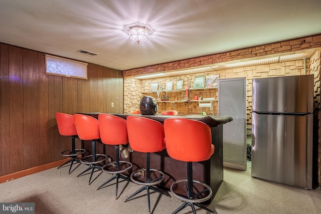 bar with stainless steel refrigerator, wood walls, and carpet floors