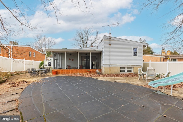 back of property featuring a sunroom, ceiling fan, a patio, and a covered pool