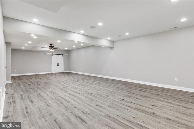 basement featuring a barn door and light wood-type flooring