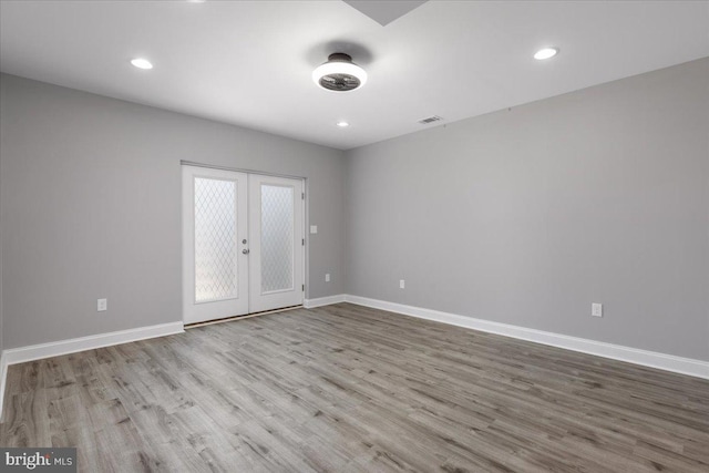 empty room featuring french doors and light hardwood / wood-style floors