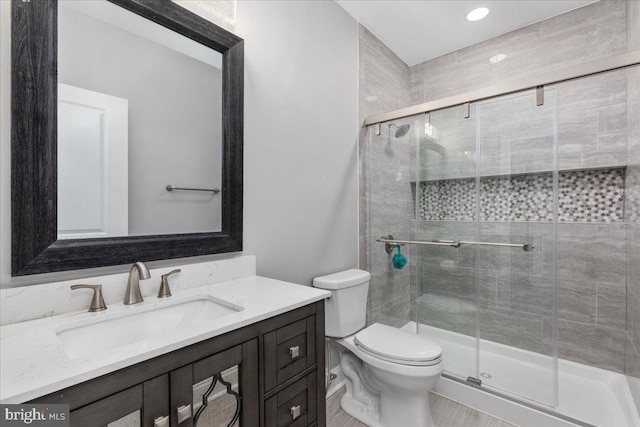 bathroom featuring vanity, toilet, and a shower with door