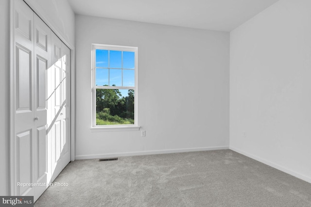 unfurnished bedroom with a closet, light carpet, and multiple windows