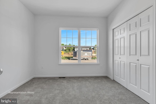 unfurnished bedroom featuring light colored carpet and a closet