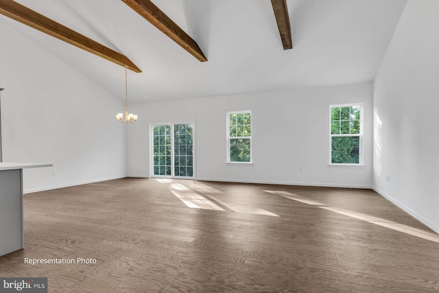 unfurnished living room featuring beamed ceiling, hardwood / wood-style floors, plenty of natural light, and a notable chandelier