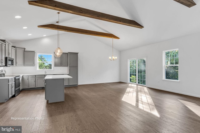 kitchen with gray cabinetry, decorative light fixtures, beamed ceiling, and appliances with stainless steel finishes