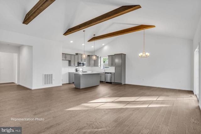 unfurnished living room with sink, beam ceiling, hardwood / wood-style flooring, high vaulted ceiling, and a chandelier