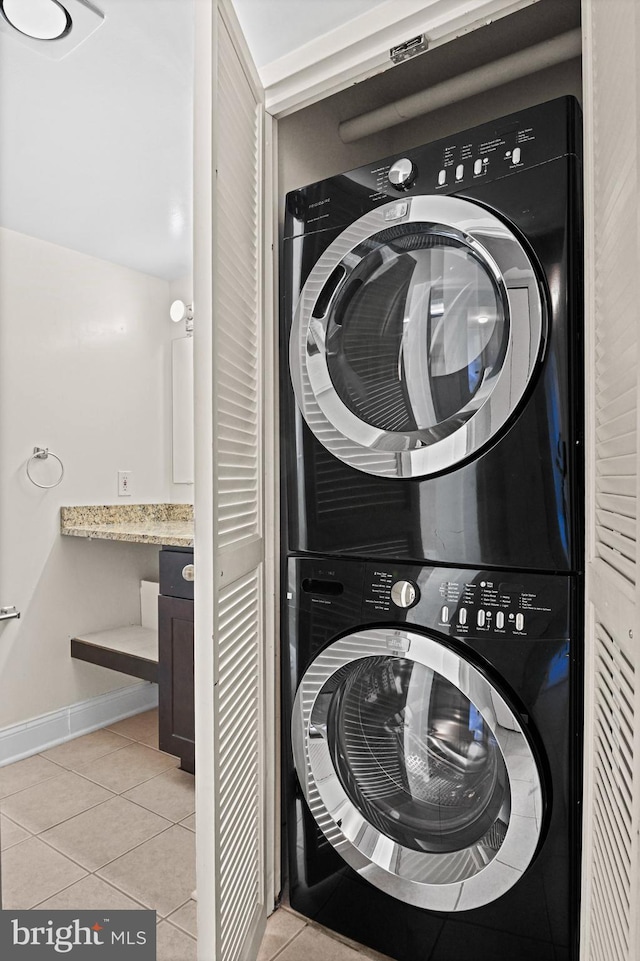 laundry room featuring light tile patterned floors and stacked washer / dryer