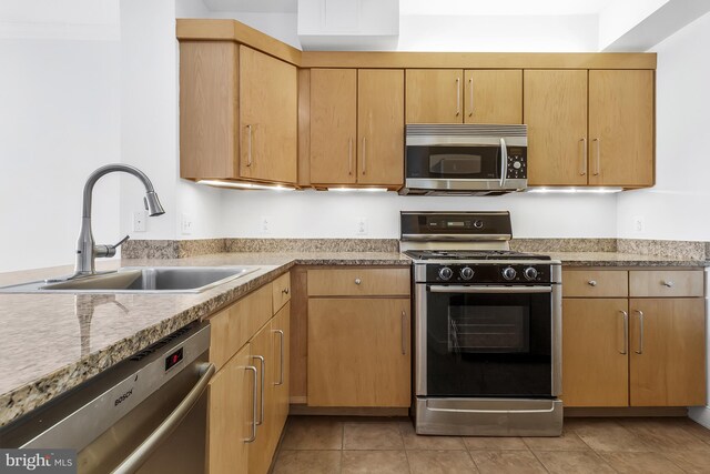 kitchen with appliances with stainless steel finishes, light stone counters, sink, light brown cabinets, and light tile patterned floors