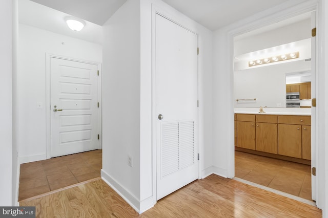 hall with light wood-type flooring and sink