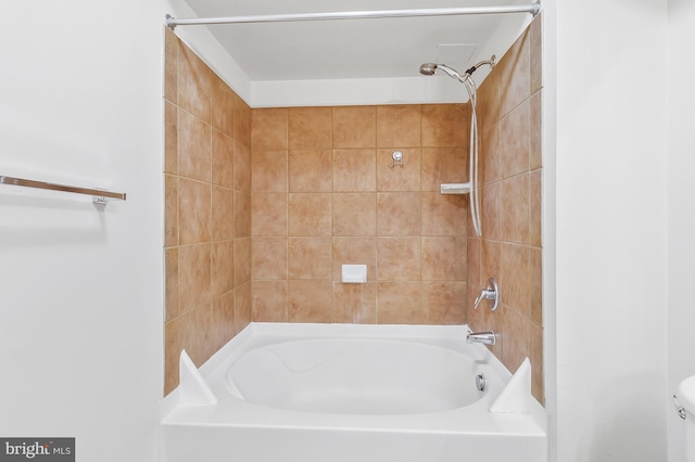 bathroom with toilet and tiled shower / bath