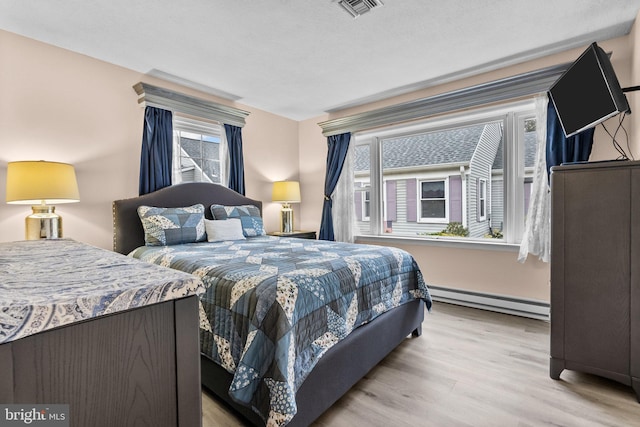 bedroom featuring a baseboard radiator and light hardwood / wood-style floors