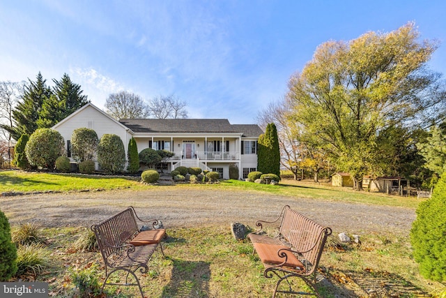 ranch-style house featuring covered porch, a front yard, and a storage shed