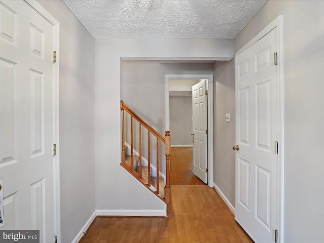 corridor featuring a textured ceiling and light hardwood / wood-style flooring