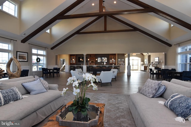 living room with hardwood / wood-style flooring, beamed ceiling, and high vaulted ceiling