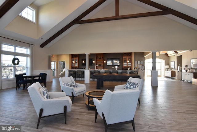 living room with a wealth of natural light, wood-type flooring, and high vaulted ceiling