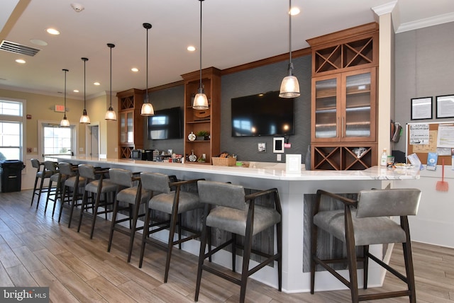 bar featuring hanging light fixtures, light wood-type flooring, and ornamental molding