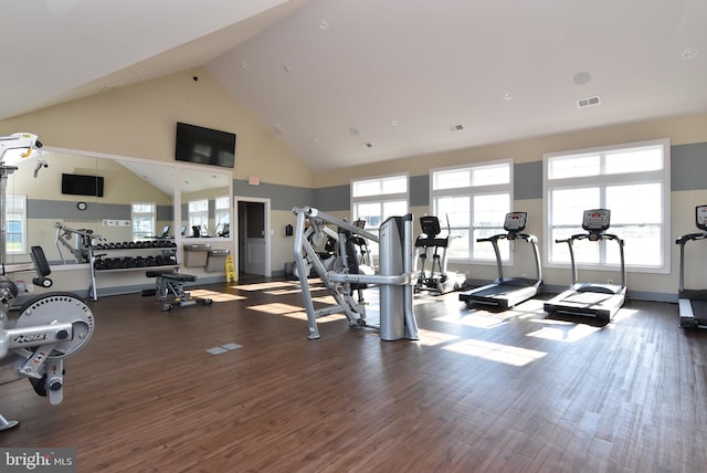 gym with a healthy amount of sunlight, dark wood-type flooring, and high vaulted ceiling