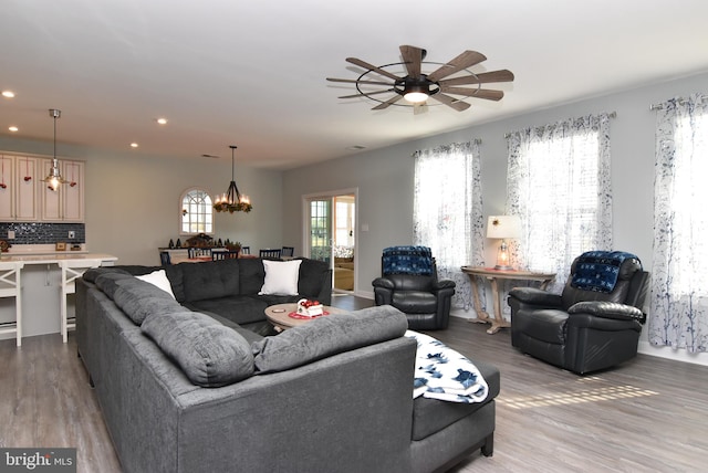 living room featuring ceiling fan with notable chandelier and hardwood / wood-style flooring