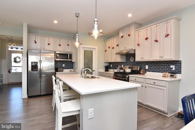 kitchen featuring stainless steel appliances, dark wood-type flooring, sink, a breakfast bar area, and an island with sink