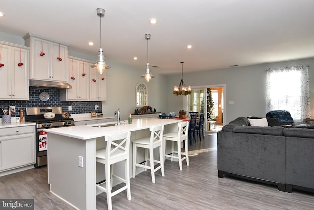 kitchen with white cabinets, a center island with sink, sink, and stainless steel range