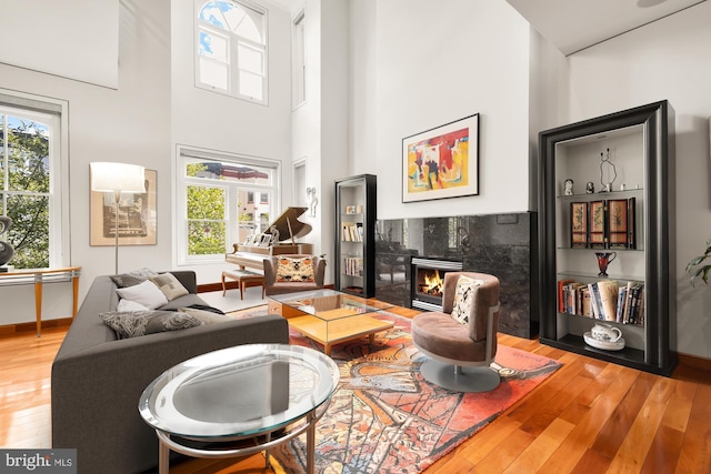 living room featuring hardwood / wood-style flooring, a fireplace, and a high ceiling