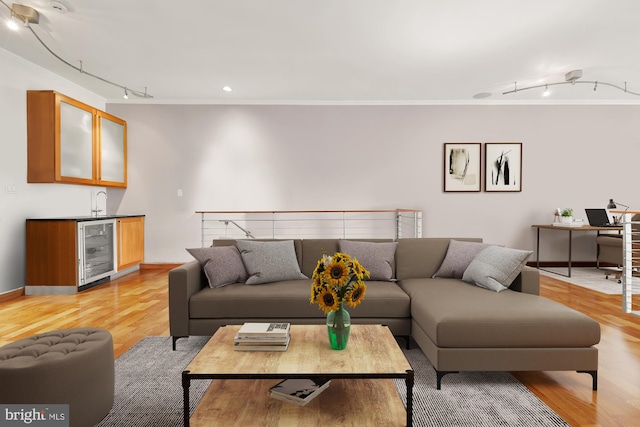 living room with rail lighting, ornamental molding, light hardwood / wood-style flooring, bar area, and wine cooler