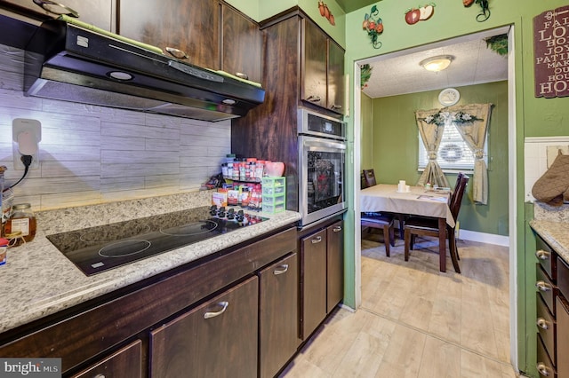 kitchen with light countertops, light wood-style flooring, stainless steel oven, under cabinet range hood, and black electric cooktop